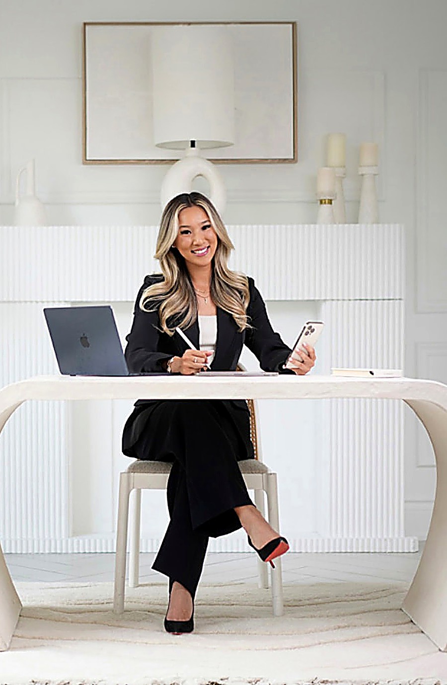 Vanessa Lin at her desk with a laptop, tablet and phone